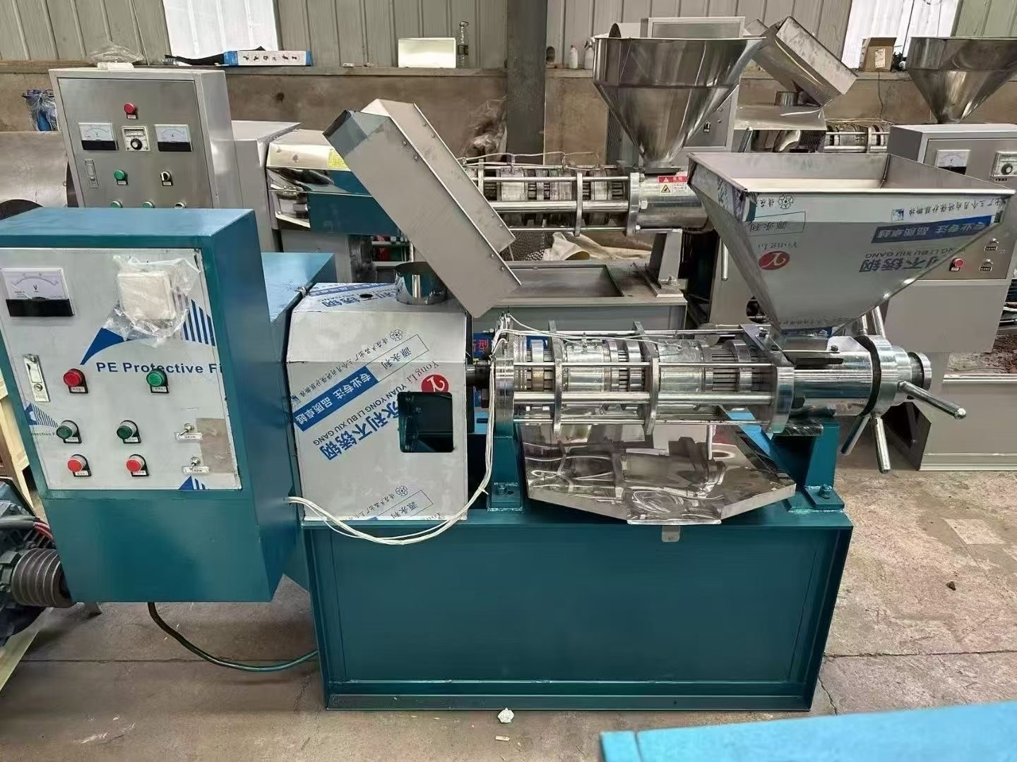 Industrial spiral oil press machine with metallic finish, multiple pressing chambers, control panel, and sturdy frame, suitable for commercial use